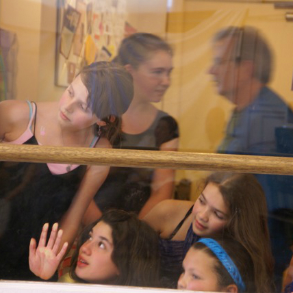 5 dancers look through the lobby window at a class in progress