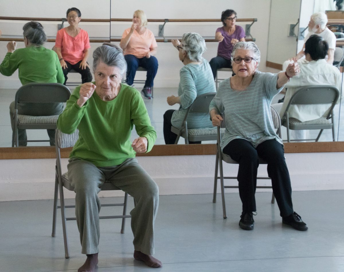 Dance for PD class students sit in chair mid movement