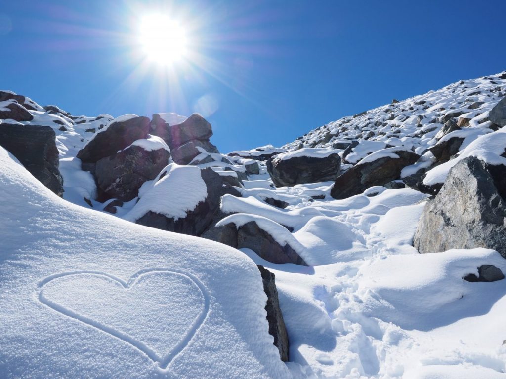 A stock photo of a snowy slope with a heart in the snow.