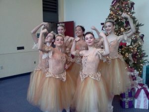 A group of dancers in costume in the lobby showing their biceps before a performance of the Nutcracker