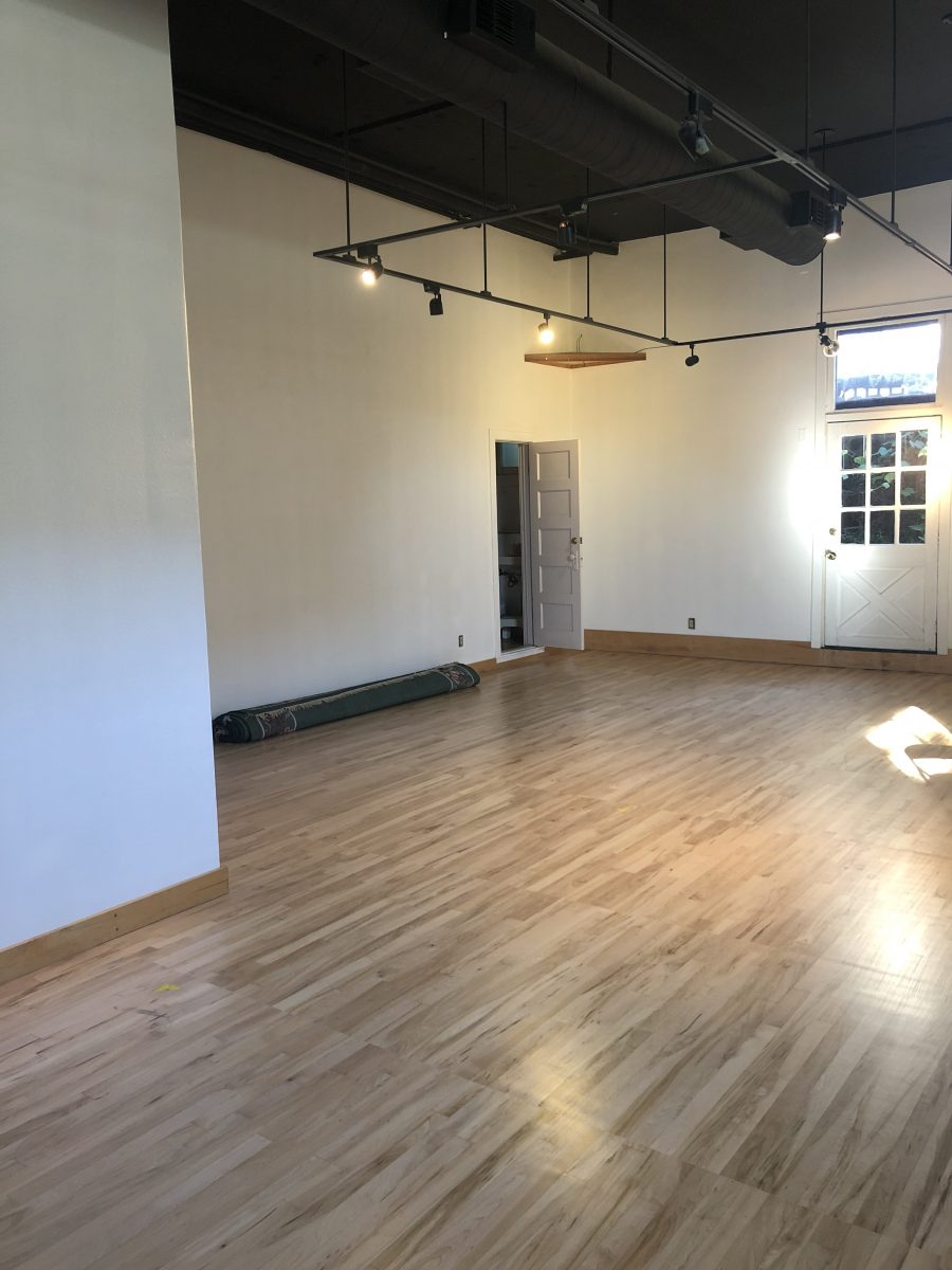 studio 3 has wood floors, no mirrors. Two doors are visible from this angle, one into the restroom and one to the outside.